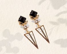 "Add a dose of style to your outfits with these striking art deco earrings. Made of brass with a luxurious 18k gold plating, they ensure a luxurious feel without the hefty price tag. These 1920s earrings come with a bold design, featuring a black stone and a minimalist triangle. The tasteful rhinestones and crystals enhance the design and add a subtle sparkle, forming the perfect combination that will turn heads. With the stylish geometric design, this bold pair will bring the wow effect to any Art Deco Metal Earrings For Evening, Clip-on Art Deco Earrings For Evening, Black Art Deco Earrings For Evening, Gold Art Deco Earrings For Party, Chic Black Earrings For Wedding, Dangle Art, 1920s Earrings, Gold Statement Jewelry, Black Crystal Earrings