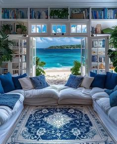 a living room filled with lots of furniture and bookshelves next to the ocean