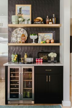 a kitchen with black cabinets and shelves filled with bottles, wine glasses, and other items