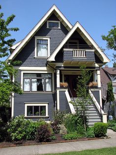 a gray house with white trim on the front and second story, surrounded by greenery