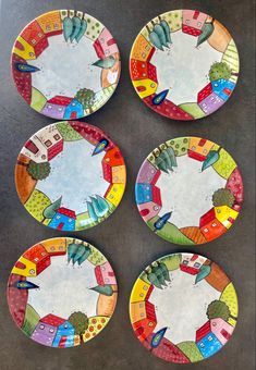 four colorful plates with houses painted on them