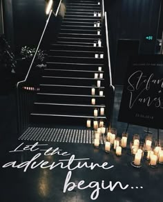 candles are lined up on the floor next to a staircase that has been decorated with writing