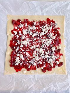 an uncooked pizza with toppings on top of it sitting on wax paper