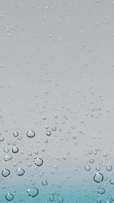 drops of water on a window pane with blue and gray colors in the background