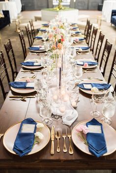 the table is set with blue napkins and place settings for an elegant dinner party