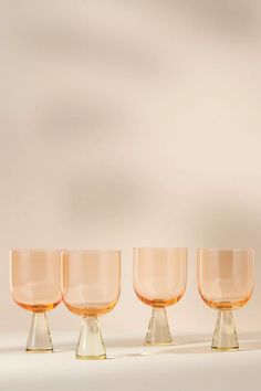 three glasses sitting next to each other on top of a white tablecloth covered floor