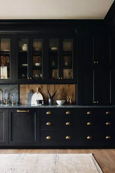 a kitchen with black cabinets and gold pulls on the doors, counter tops and drawers