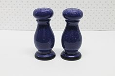 two blue candlesticks sitting next to each other on a white counter top with polka dots