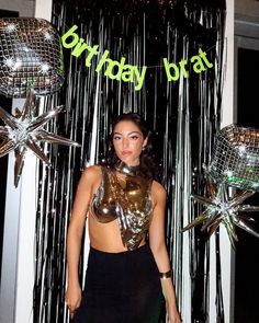 a woman standing in front of balloons and streamers with the words birthday brat on it