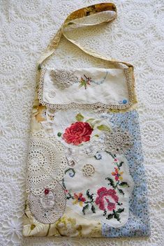 an old purse is laying on a white lace tablecloth with flowers and crochet