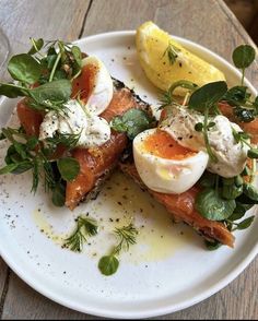 a white plate topped with food on top of a wooden table next to a lemon wedge