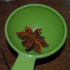 anisette in a green bowl on top of a wooden table next to a spoon