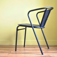 a black chair sitting on top of a hard wood floor next to a yellow wall