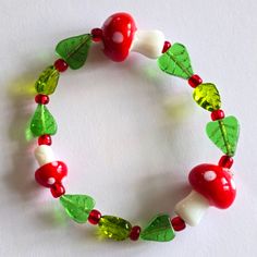 a close up of a bracelet made out of glass beads and green leafy leaves