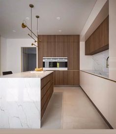 a modern kitchen with marble counter tops and wooden cabinetry, along with an island in the middle