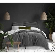 a bedroom with black walls and white flooring is pictured in this image, there are plants on either side of the bed