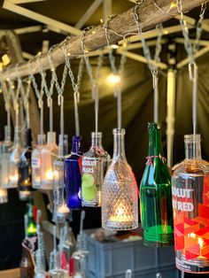 many different colored bottles are hanging from the ceiling with string lights on each one side