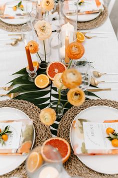 the table is set with orange slices and place settings