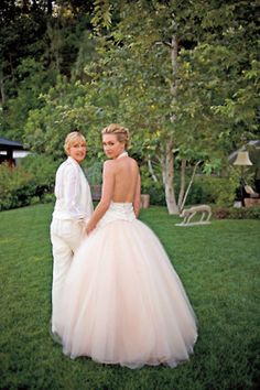 two people standing in the grass near each other wearing wedding dresses and tuxedos