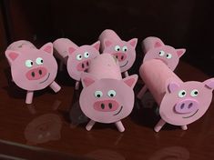 some pink pigs are standing next to each other on a wooden table and looking at the camera