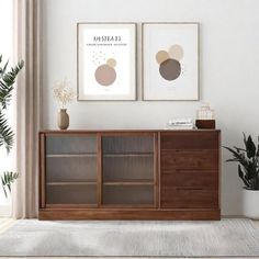 a living room with two framed pictures on the wall and a wooden cabinet in front of it