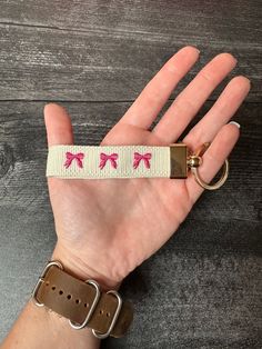 a hand holding onto a wrist strap with pink bows on it