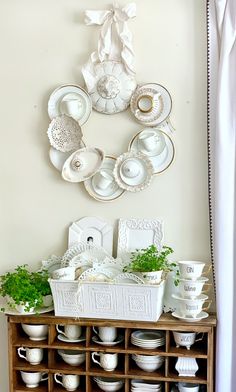 a shelf filled with dishes and plates next to a wall mounted wreath on the wall