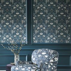 a blue chair sitting next to a vase with flowers in it on top of a table