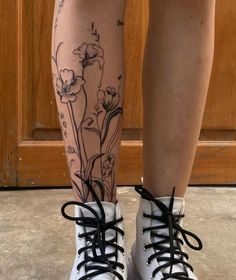 a woman's legs with flowers on them and black laces around the ankles