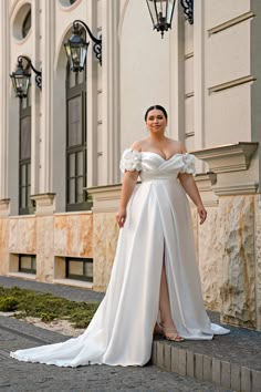 a woman in a white dress is standing on the steps near a light pole and lamppost