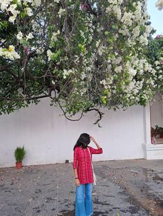 a woman standing under a tree with white flowers