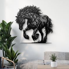 a black and white horse is hanging on the wall next to a plant in a living room