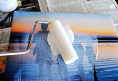 an image of a man in the water is being displayed on a table with paint and paper