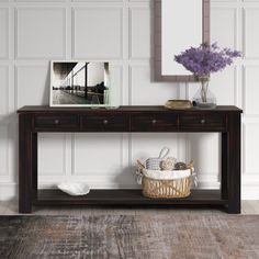 a wooden table with two drawers and a basket on it next to a framed photograph