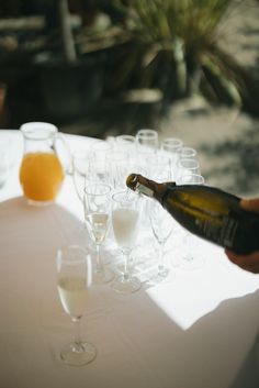 a person pouring champagne into wine glasses on a table