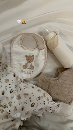 a baby's diaper, bottle and bib laying on top of a bed