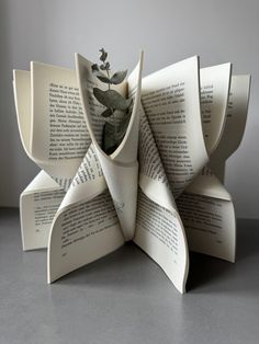 an origami book sculpture made out of books with flowers in the middle, on a table