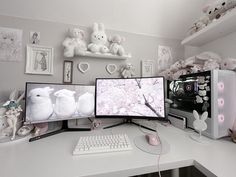 three computer monitors sitting on top of a desk next to stuffed animals and other items