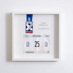 a white frame with a blue ribbon hanging on the wall