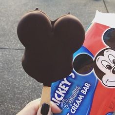 a person holding a mickey mouse ice cream bar