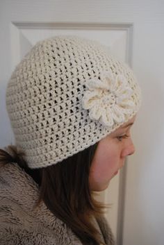 a woman wearing a white crocheted hat with a flower