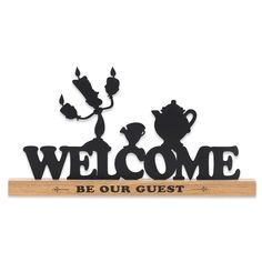 a welcome sign with the words be our guest and teapots in black on a white background