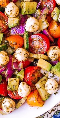 a white plate topped with lots of veggies and potatoes on top of a table