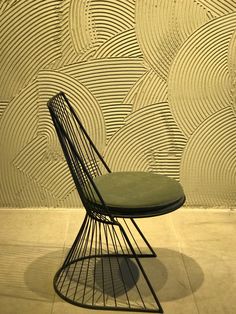 a green chair sitting in front of a wall with wavy designs on it's sides