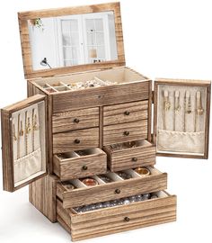 an open wooden jewelry box sitting on top of a white table next to a mirror