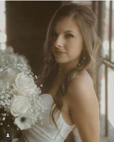 a beautiful woman holding a bouquet of white flowers