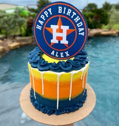 a birthday cake that is sitting on top of a table near a pool with a happy birthday sign