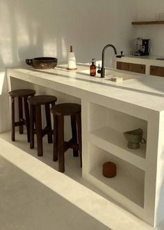 a kitchen with white counter tops and stools next to a bar area in the center