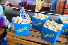 three blue boxes filled with popcorn sitting on top of a wooden table next to other items