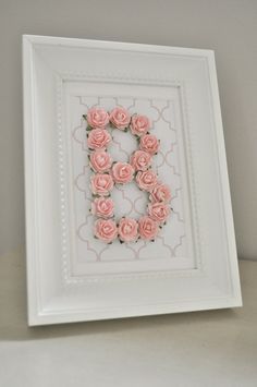 a white frame with some pink flowers in the shape of a number 8 on it